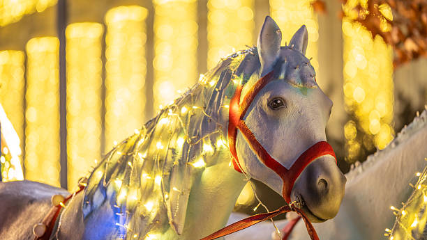 istock White horse statue decorated with glowing string lights in autumn park 2253784189
