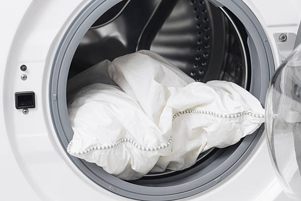 istock Pillow washing inside modern washing machine. White pillow in drum closeup. Home laundry care concept. 2253784585