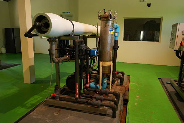 A detailed view of an industrial water purification system, showcasing its intricate network of pipes, tanks, and control elements, set against a green floor.