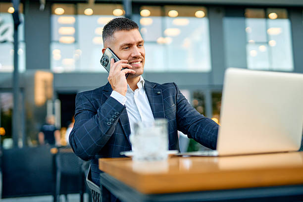 istock Professional businessman talking on phone using laptop outdoors 2253794045