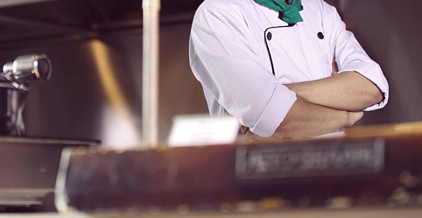 istock professional chef stands and working in a modern kitchen, wearing a white uniform. This image conveys expertise, focus, and readiness in a high demand culinary environment for restaurant profile background 2253799849