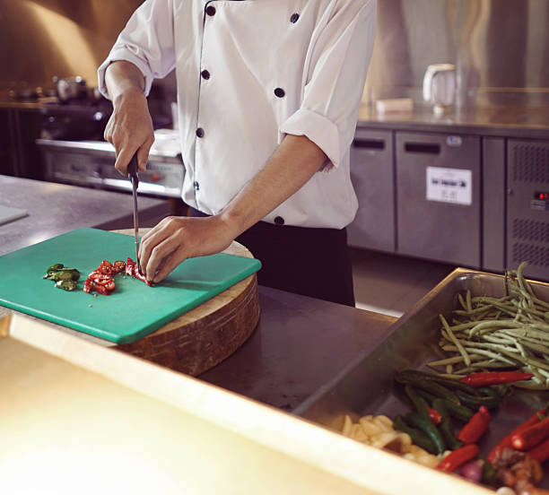 istock professional chef stands and working in a modern kitchen, wearing a white uniform. This image conveys expertise, focus, and readiness in a high demand culinary environment for restaurant profile background 2253799884