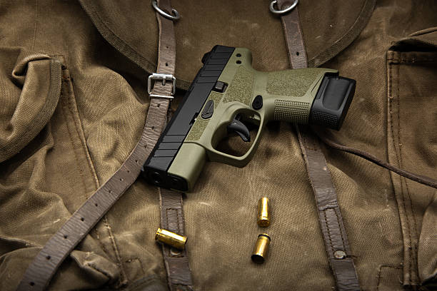 istock Olive green compact handgun with empty shell casings on a vintage canvas military bag. 2253799994