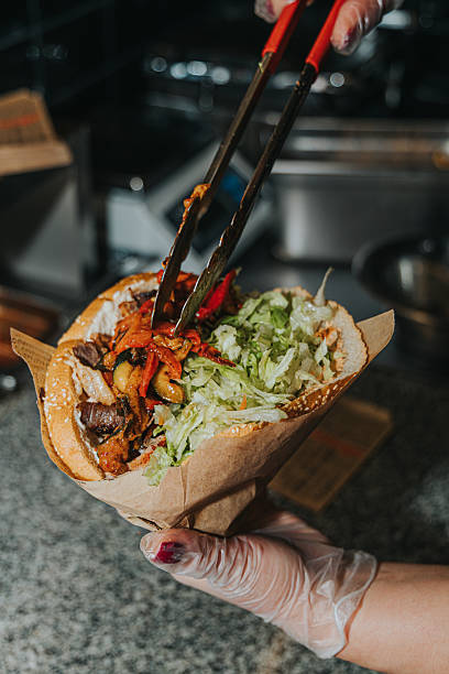 The process of cooking kebab in a bun. Chef's hands. Sauces, vegetables, meat