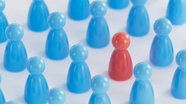 istock Standout Red Token: Contrast in a Group of Blue Game Pieces 2253804320