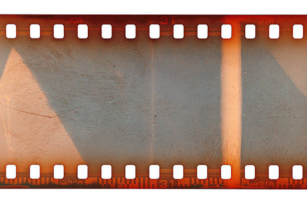 Dusty and grungy 35mm film texture or surface. Perforated scratched camera film isolated on white background.