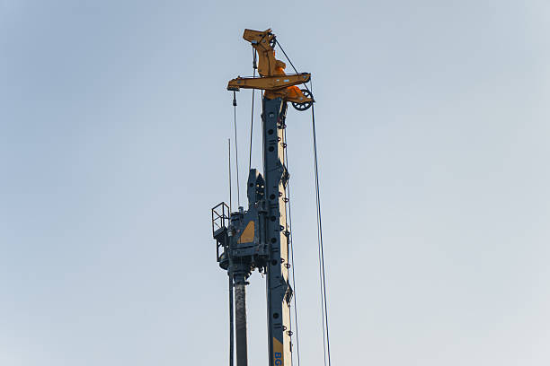 istock Tall construction piling rig with hydraulic drilling equipment and suspended cables rising vertically against clear sky during heavy foundation works 2253806573