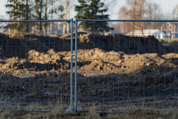 istock Construction site perimeter secured with wire mesh fence separating public area from excavation ground and soil heaps during infrastructure works 2253806586