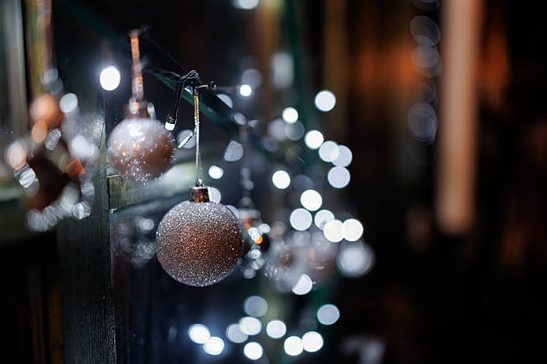 Silver colored ornaments and Christmas lights on window shining in night