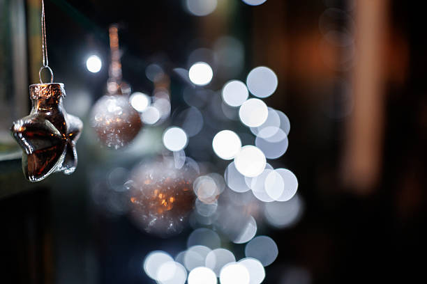 Silver colored ornaments and Christmas lights on window shining in night