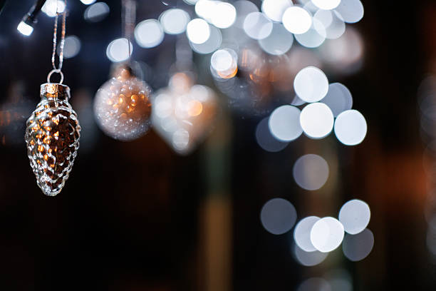Silver colored ornaments and Christmas lights on window shining in night