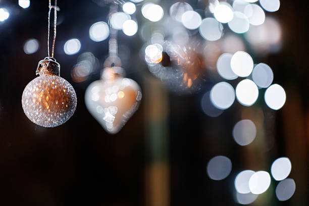 Silver colored ornaments and Christmas lights on window shining in night
