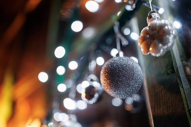 Silver colored ornaments and Christmas lights on window shining in night