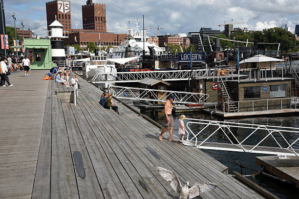 Aker Brygge Promenade Oslo with several people captured during a cloudy day in summer season.