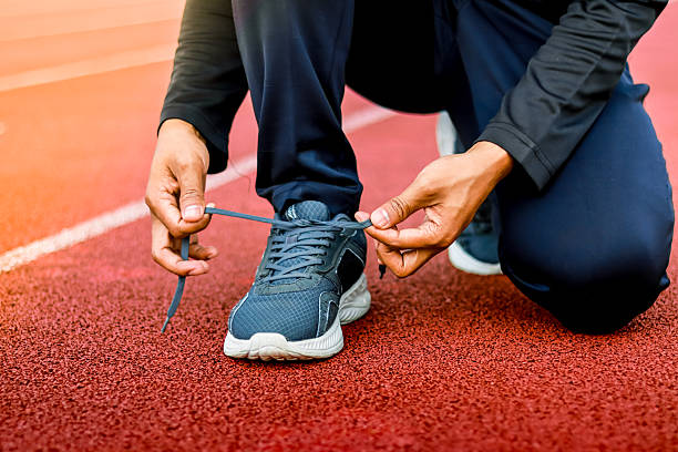 istock Runner tying shoelaces on red track, preparing for race or workout 2253813395