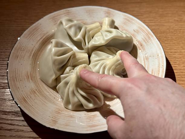 istock Homemade Khinkali Hot And Inviting, Warm Kitchen Scene With Hand Selecting Freshly Cooked Khinkali, Picture Captures Home Cook About To Enjoy Freshly Steamed Dumpling In Cozy Setting 2253813986