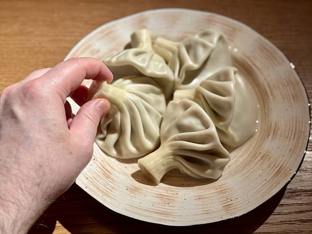 istock Homemade Khinkali Hot And Inviting, Warm Kitchen Scene With Hand Selecting Freshly Cooked Khinkali, Picture Captures Home Cook About To Enjoy Freshly Steamed Dumpling In Cozy Setting 2253814128