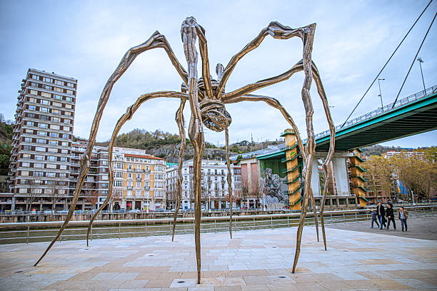 November, 2025. Bilbao, Spain.  A sculpture by the artist Louise Bourgeois by the Guggenheim museum with a group of tourists passing by.