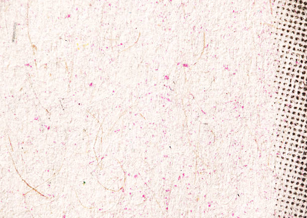 Macro image of light, fibrous paper scattered with small pink speckles. A black halftone dot pattern appears along the right edge, creating contrast in texture and tone.
