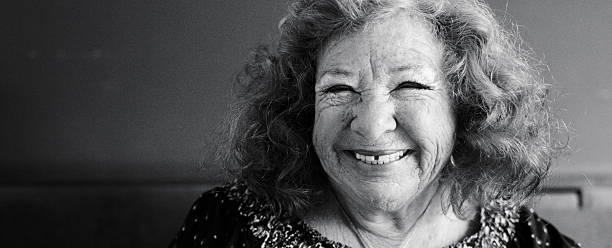 Happy elderly Asian woman lying in bed and peacefully looking out the window at home.