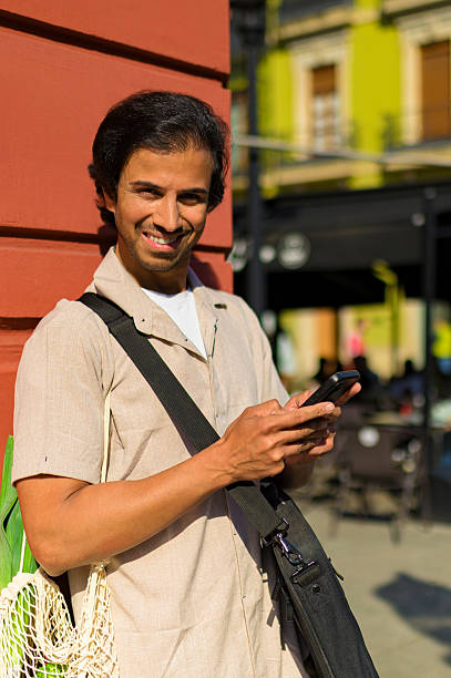 istock Young adult indian man using smartphone with reusable bag 2253833159