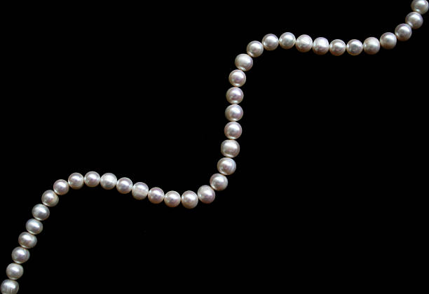 istock White pearls on the black silk as background 2253834112