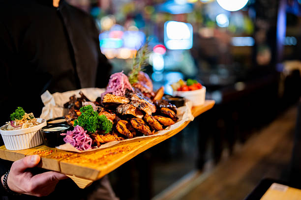 istock A hearty, assorted grilled meat platter with ribs, potatoes, and salad is held by a server in a dimly lit restaurant. 2253836754
