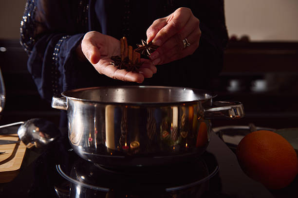 istock Winter Kitchen Scene: Woman Preparing Mulled Wine With Spices Beside A Pot And Orange 2253839964