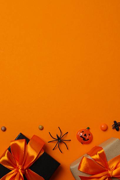 istock Halloween poscard with festive gift boxes and decorations on orange background . Top view, space for text 2253842212