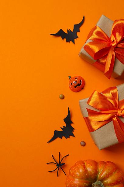 istock Halloween poscard with festive gift boxes and decorations on orange background . Top view, space for text 2253842214