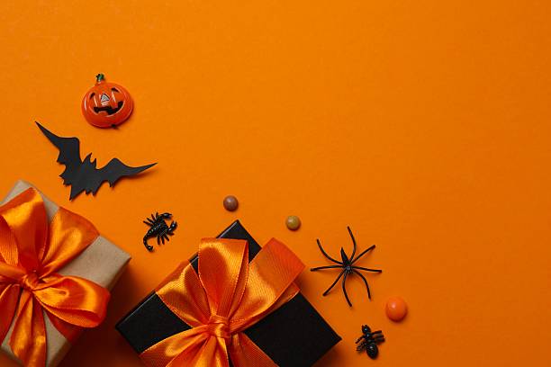 istock Halloween poscard with festive gift boxes and decorations on orange background . Top view, space for text 2253842219