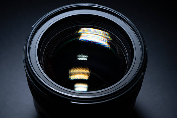 istock Detailed front view of camera lens glass with strong reflections in studio lighting. 2253842828