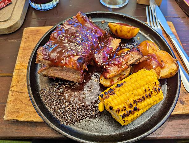 istock Appetizing BBQ Pork Ribs with Roasted Corn and Potatoes on a Rustic Plate 2253850701