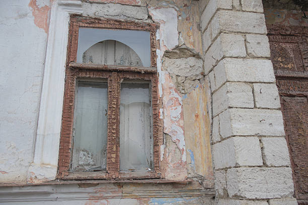 Old Abandoned Building Window with Peeling Paint and Weathered Stone Wall.