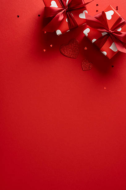 istock Red vertical backdrop with two gift boxes tied with ribbons and white heart patterns. Perfect for Valentine greetings, romance, gift ideas, love moments, and festive celebration imagery 2253853685