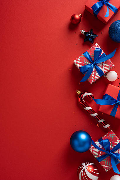 istock Colorful vertical presents with blue ribbons and shiny ornaments on a bold red backdrop evoke Christmas and New Year celebrations, creating a cheerful holiday mood and festive gift-giving atmosphere 2253853686