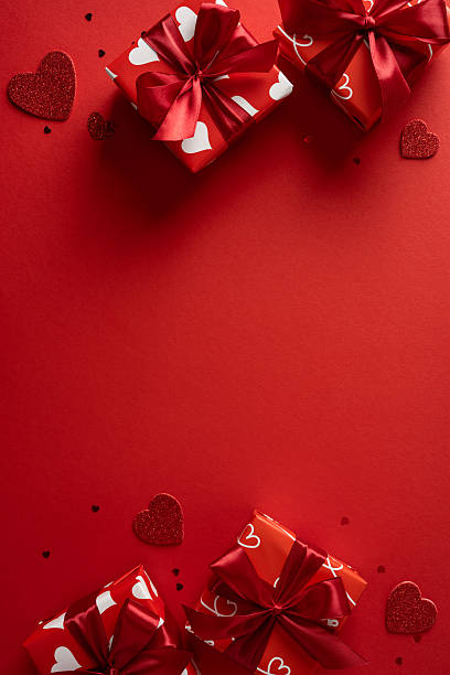 istock Vibrant vertical red backdrop features wrapped gift boxes with satin ribbons and scattered heart shapes, conveying a romantic Valentine mood perfect for gift, love, and celebration themes 2253853701