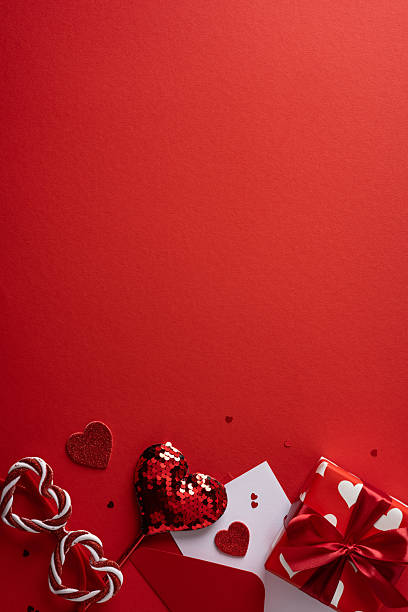 istock A vertical romantic red Valentine scene featuring a gift, heart shapes, candy cane, and a greeting card set against a bold red background 2253853712
