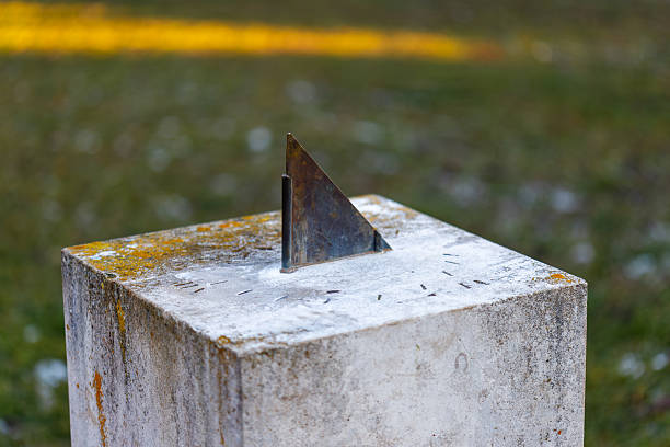 Weathered sundial on concrete pedestal indicating time outdoors