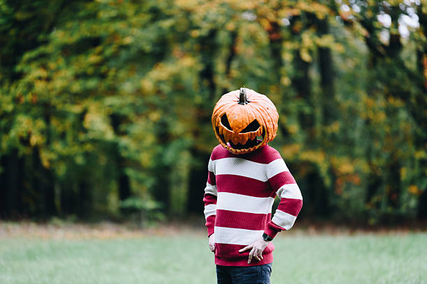 istock Person Wearing a Pumpkin Head Standing Outdoors in Autumn 2253855262