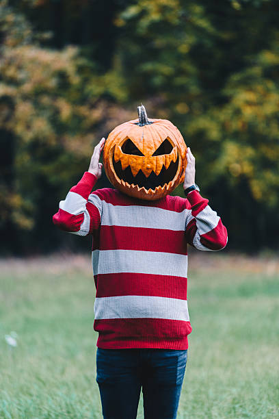 istock Person Wearing a Pumpkin Head Standing Outdoors in Autumn 2253855325