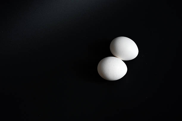 istock Two fresh white chicken eggs on a ceramic plate over a white and black 2253858026