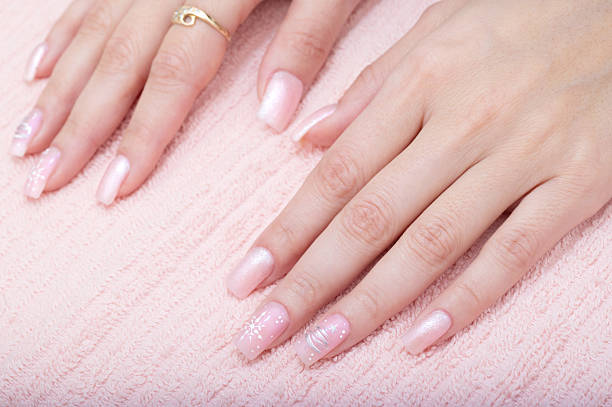 Young female hands with beautifully manicured fingernails on the pink towel.