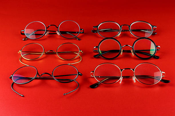 Assorted old fashioned metal eyeglass frames arranged on a red surface