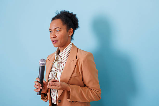 istock Woman public speaker holding microphone and communicating new ideas during business presentation 2253861649