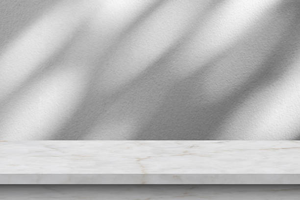 istock Marble table with tree shadow drop on white wall background for mockup product display 2253862329