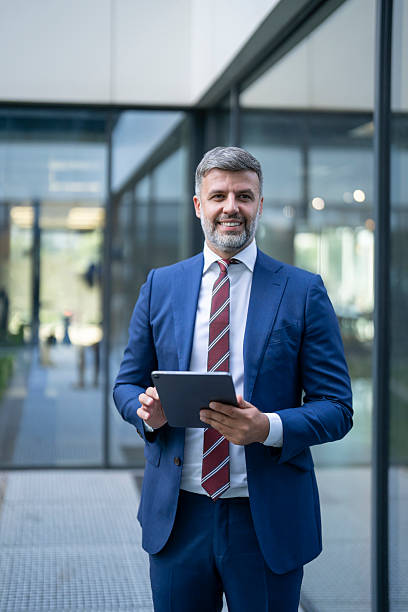 Smiling businessman using digital tablet outside modern office building