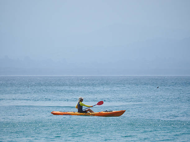 Horizontal seascape photo of a man paddling a kayak in the ocean at Wategos Beach, Byron Bay, NSW in Summer
