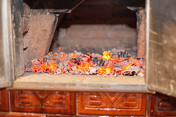 Hot glowing embers spread across the floor of a wood fired brick oven. Traditional oven heat background used for bread baking and rustic cooking concepts.