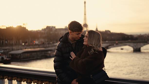 istock Young couple embracing on a bridge in Paris during sunset 2253867204
